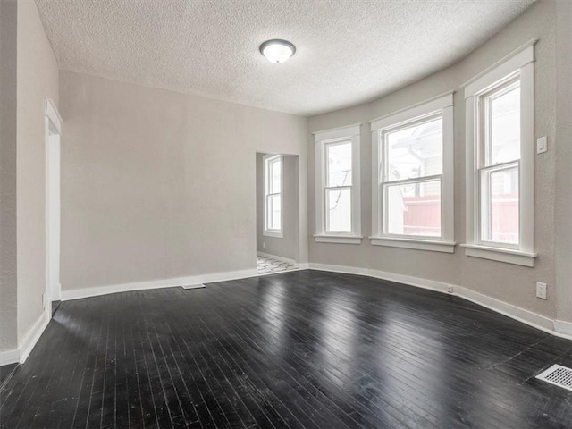 empty room with a textured ceiling and dark hardwood / wood-style floors