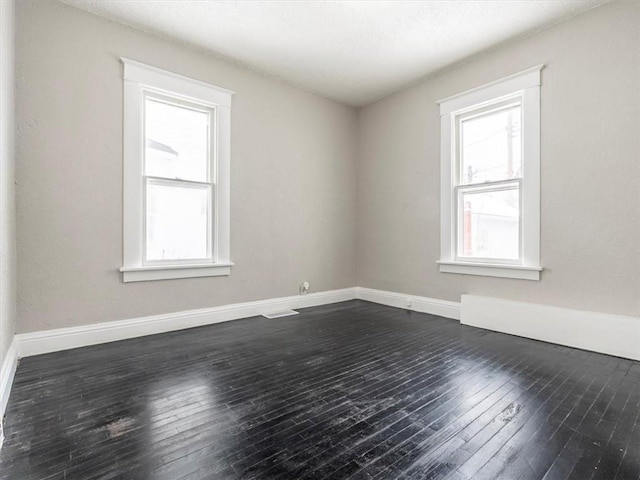 unfurnished room with a wealth of natural light and dark hardwood / wood-style flooring