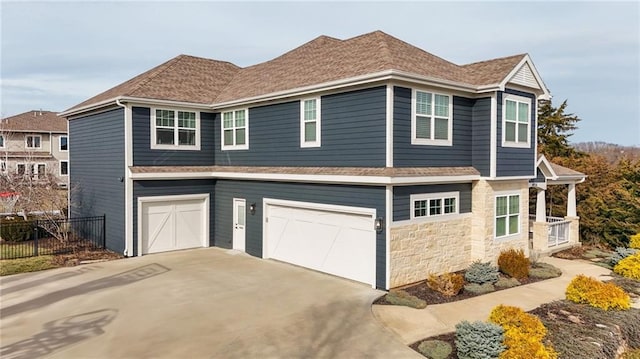 view of property exterior featuring driveway, a shingled roof, stone siding, an attached garage, and fence