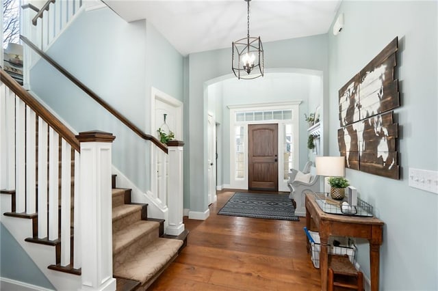 foyer with baseboards, stairs, a chandelier, and hardwood / wood-style floors