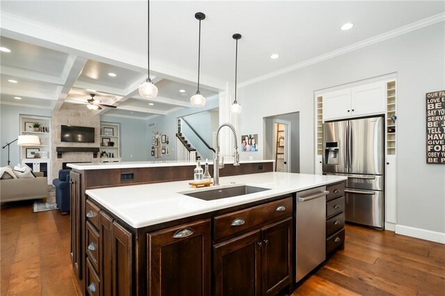 kitchen with ornamental molding, dark wood-type flooring, light countertops, a sink, and appliances with stainless steel finishes