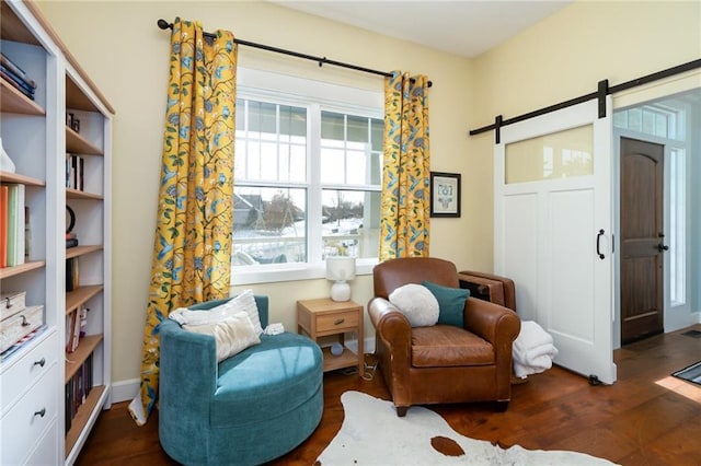 sitting room featuring a barn door and wood finished floors