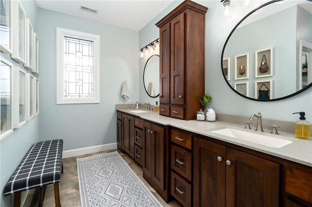 bathroom featuring visible vents, a sink, baseboards, and double vanity