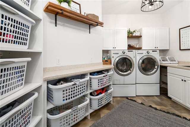 washroom featuring washing machine and dryer, cabinet space, and a notable chandelier