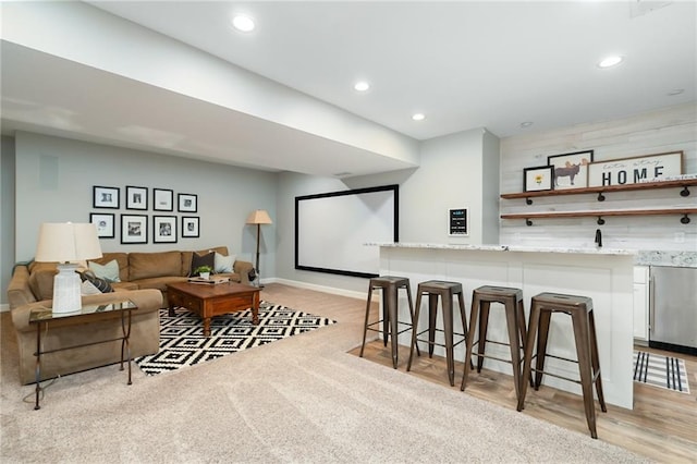 home theater room with indoor wet bar, recessed lighting, baseboards, and light colored carpet