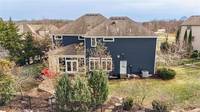 back of property featuring a lawn, fence, roof with shingles, and cooling unit