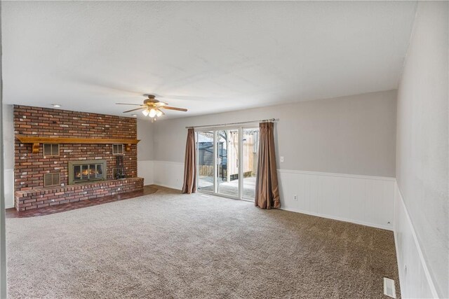 unfurnished living room featuring ceiling fan, carpet, and a brick fireplace