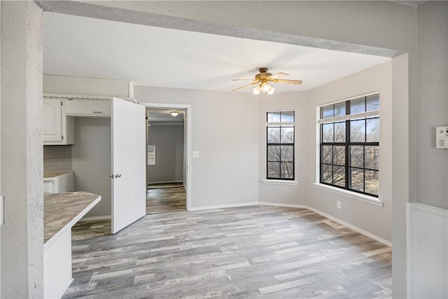 empty room with ceiling fan and light wood-type flooring