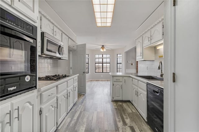 kitchen featuring hardwood / wood-style floors, sink, black appliances, kitchen peninsula, and white cabinets