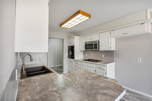 kitchen with sink, black appliances, white cabinetry, and decorative backsplash