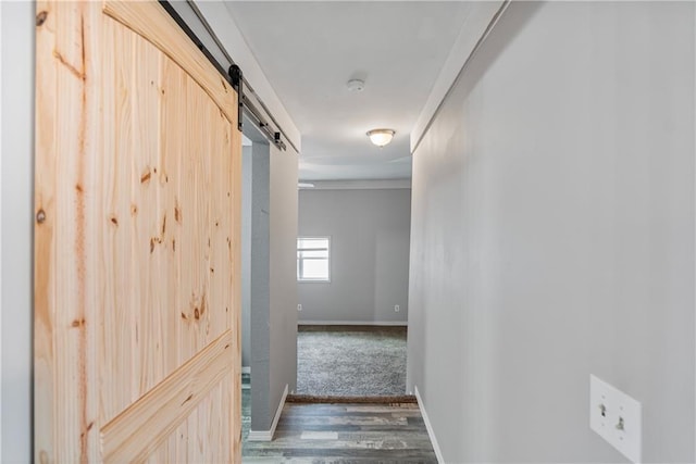 hallway with a barn door and dark hardwood / wood-style floors