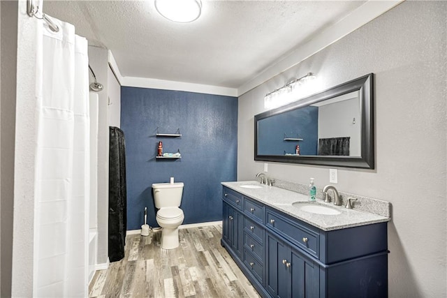 full bathroom featuring toilet, shower / bath combo with shower curtain, wood-type flooring, a textured ceiling, and vanity