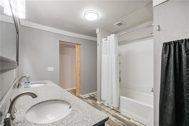 bathroom with hardwood / wood-style flooring, a textured ceiling, shower / tub combo with curtain, and vanity