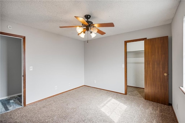 unfurnished bedroom with a walk in closet, carpet floors, a closet, ceiling fan, and a textured ceiling