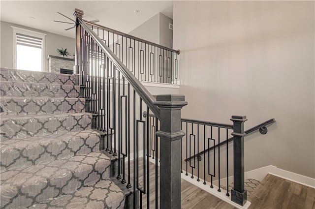 staircase with a fireplace, baseboards, and wood finished floors