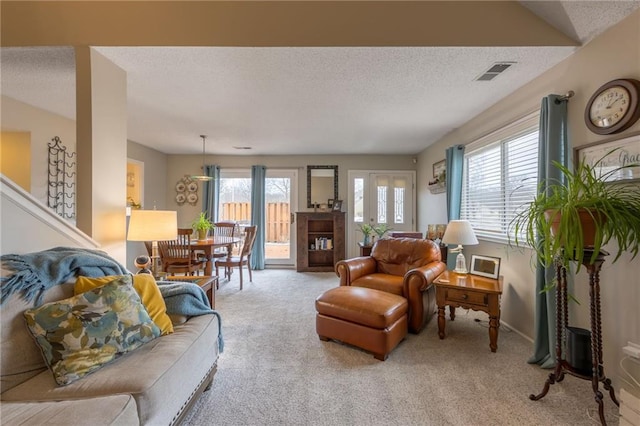 carpeted living room featuring a wealth of natural light, visible vents, and a textured ceiling