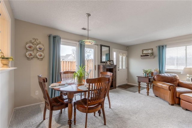 dining space featuring visible vents, light colored carpet, a textured ceiling, and baseboards