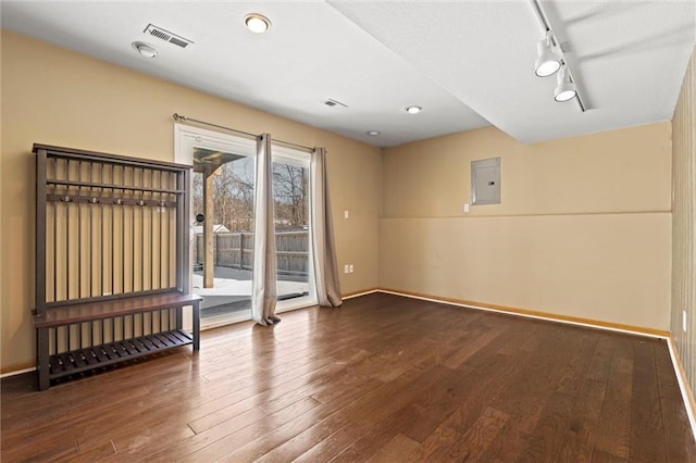 spare room featuring visible vents, wood finished floors, electric panel, and baseboards