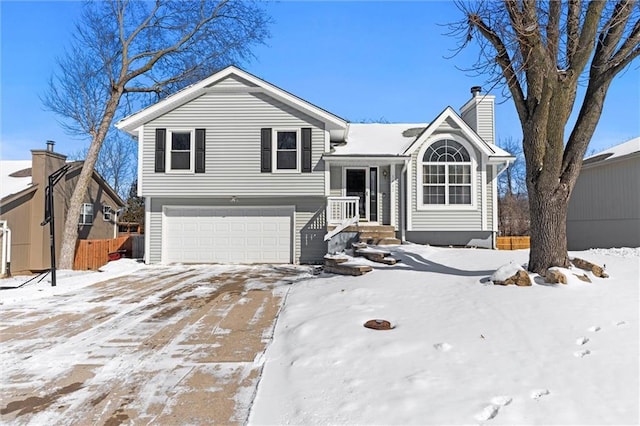 tri-level home featuring a chimney, a garage, and fence