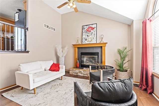 living room with a fireplace, lofted ceiling, wood finished floors, and visible vents