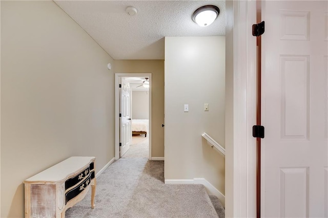 corridor with a textured ceiling and light carpet