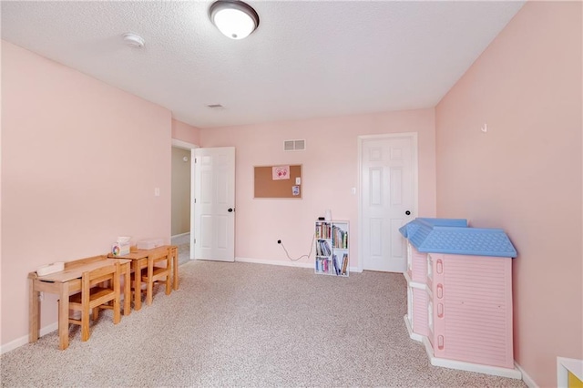 rec room with a textured ceiling and light carpet