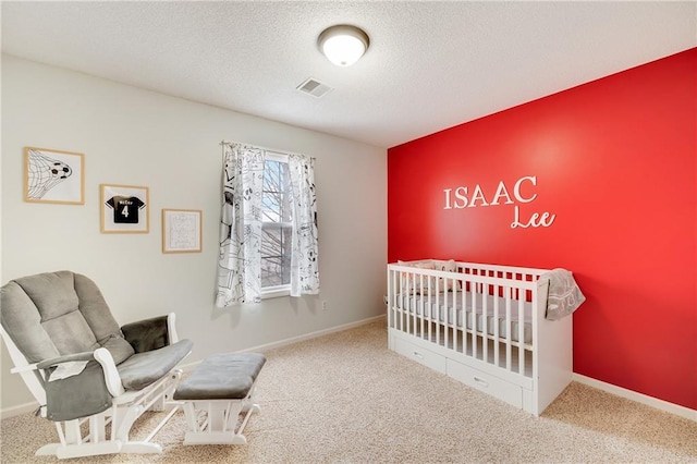 carpeted bedroom featuring a crib and a textured ceiling