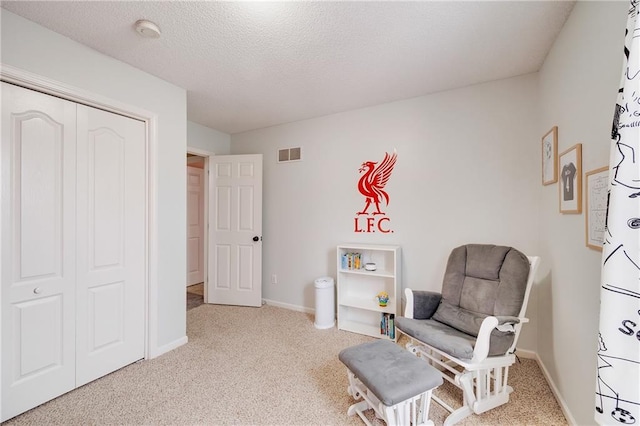 sitting room featuring light carpet and a textured ceiling