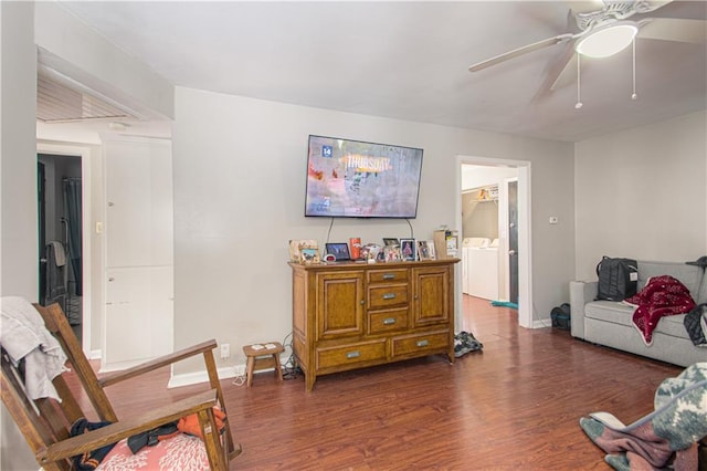 living area featuring a ceiling fan, dark wood-style flooring, washer and clothes dryer, and baseboards