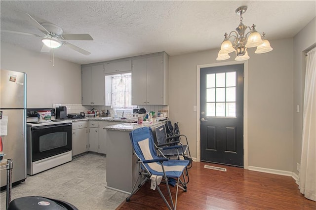 kitchen featuring tasteful backsplash, freestanding refrigerator, visible vents, and range with electric stovetop