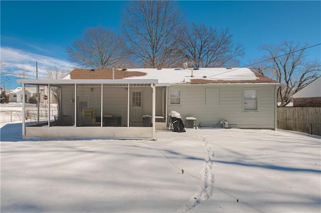 snow covered property featuring central AC, fence, and a sunroom