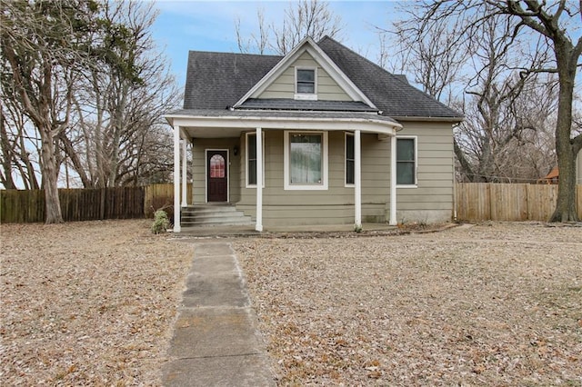 bungalow featuring a porch, roof with shingles, and fence private yard