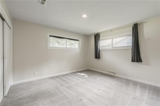 11413 Palmer Ave, Kansas City, MO 64134 - unfurnished bedroom featuring a textured ceiling, multiple windows, a closet, and carpet flooring