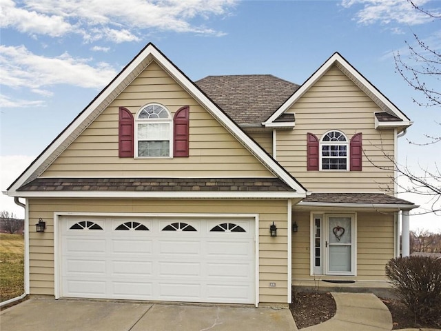 traditional home with a garage, roof with shingles, and driveway