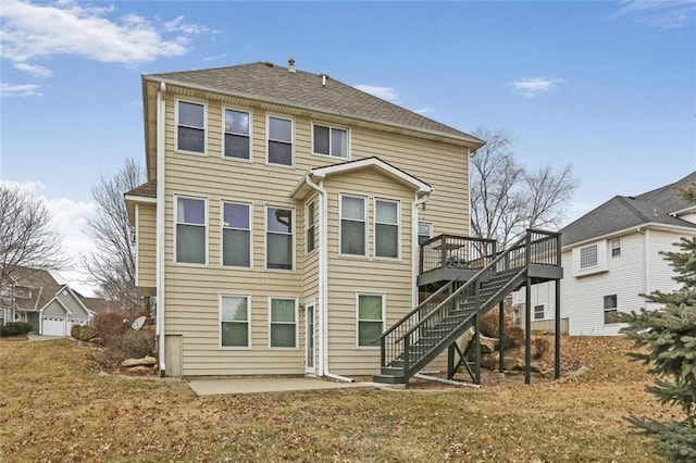 rear view of house with roof with shingles, stairway, a deck, and a patio