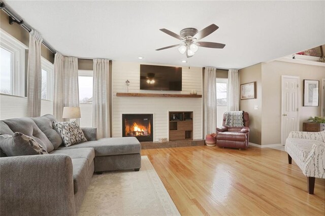 living area featuring a large fireplace, plenty of natural light, wood finished floors, and baseboards