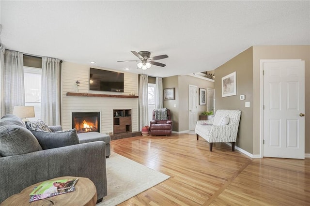 living area with light wood finished floors, a fireplace, baseboards, and a wealth of natural light