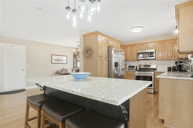 kitchen featuring stainless steel appliances, tasteful backsplash, visible vents, light brown cabinetry, and a sink