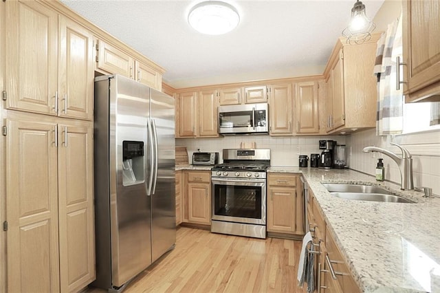 kitchen featuring light wood-type flooring, light brown cabinets, appliances with stainless steel finishes, and a sink