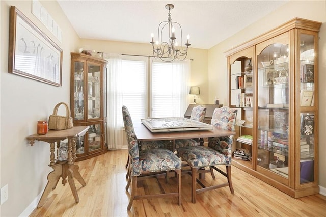 dining room featuring visible vents, light wood-style flooring, baseboards, and an inviting chandelier