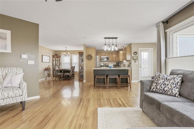 living area with light wood-style flooring, baseboards, and a wealth of natural light