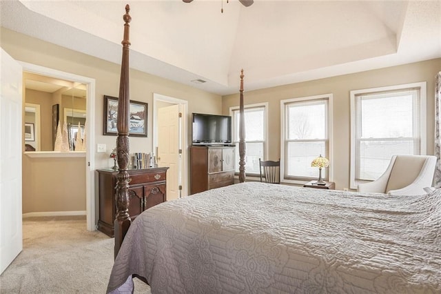 carpeted bedroom featuring a tray ceiling, visible vents, ensuite bathroom, ceiling fan, and baseboards