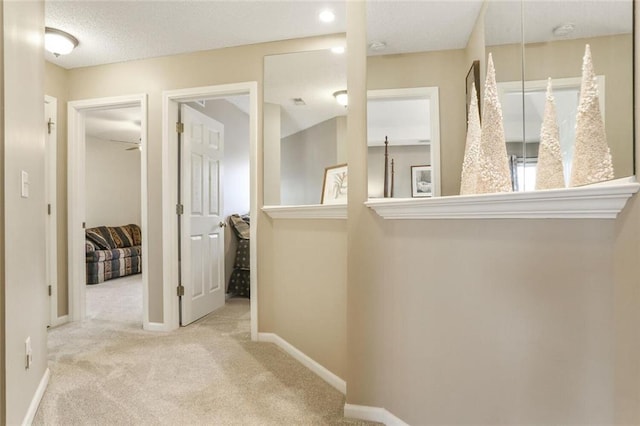 corridor featuring carpet, baseboards, and a textured ceiling