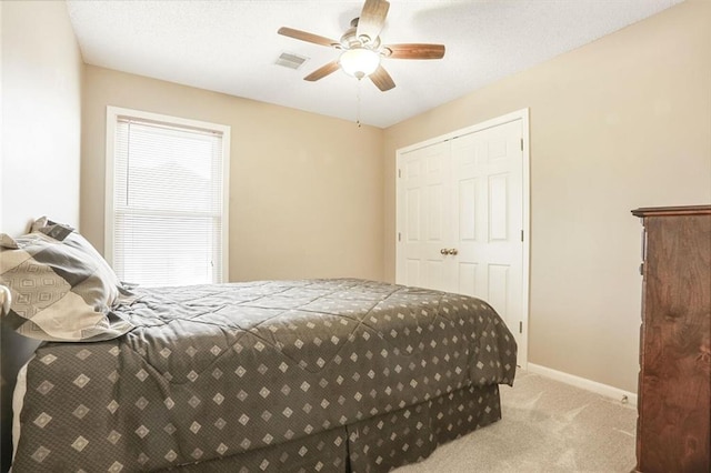 carpeted bedroom featuring baseboards, visible vents, ceiling fan, and a textured ceiling