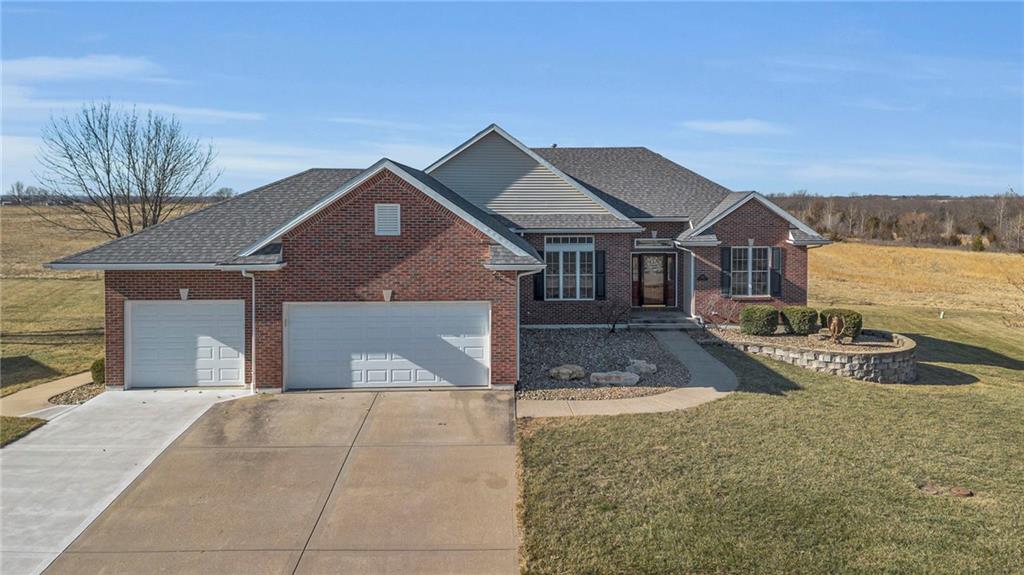 view of front of property featuring a front yard, brick siding, a garage, and driveway