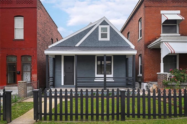 view of front of property featuring a fenced front yard, a front lawn, a porch, and brick siding