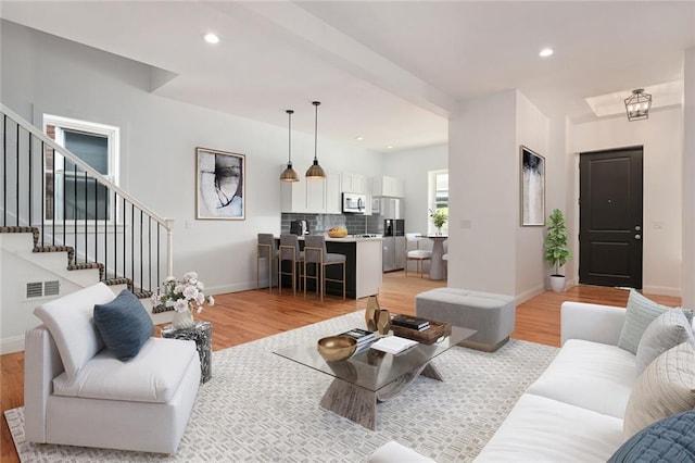 living area featuring stairs, light wood-style flooring, and recessed lighting