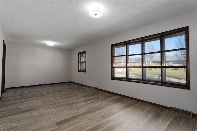 unfurnished room with visible vents and light wood finished floors