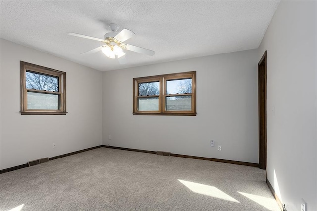 empty room with baseboards, a textured ceiling, visible vents, and carpet flooring