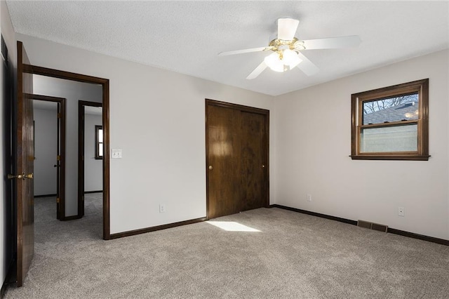 unfurnished bedroom featuring light carpet, baseboards, visible vents, and a closet